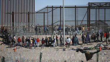 Migrantes formados después de ser detenidos por las autoridades migratorias de Estados Unidos en el muro fronterizo, el miércoles 27 de diciembre de 2023, en una imagen captada desde Ciudad Juárez, México. (AP Foto/Christian Chavez)