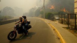 ARCHIVO - Residentes evacúan en una motocicleta entre incendios forestales en Viña del Mar, Chile, el 3 de febrero de 2024. Los científicos dicen que el cambio climático crea condiciones que hacen más probables la sequía y los incendios forestales que afectan ahora a Sudamérica. (AP Foto/Esteban Felix, Archivo)