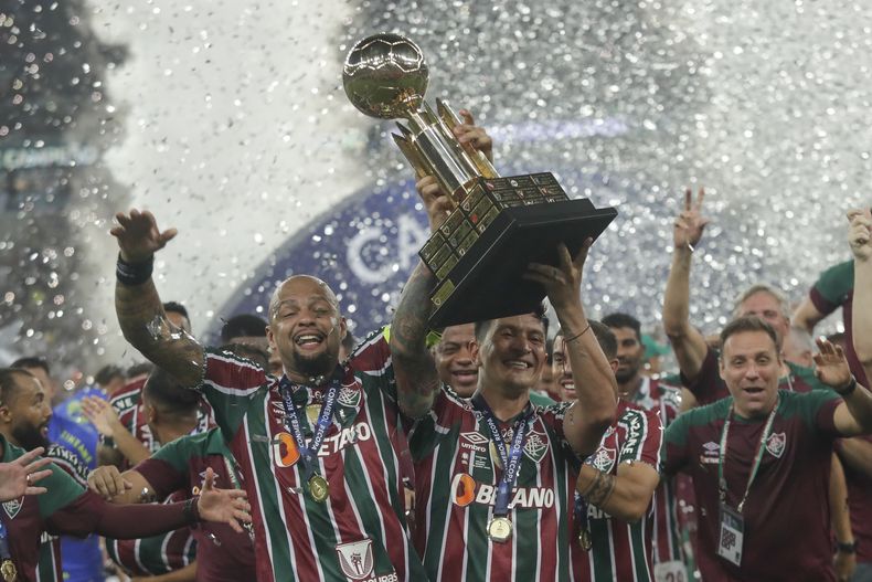 Germán Cano (centro) y Felipe Melo, de Fluminense, alzan el trofeo de la Recopa Sudamericana, luego de vencer a Liga Deportiva Universitaria en el Maracaná, el jueves 29 de febrero de 2024 (AP Foto/Bruna Prado)