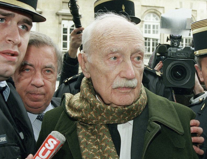 ARCHIVO - El político francés Maurice Papon flanqueado por la policía en París, el 17 de febrero de 2007. El presidente Alberto Fernández anunció el martes 9 de mayo de 2023 que Argentina retira la Orden de Mayo que había sido otorgada en 1979 al político francés. Papon, quien fue condenado en Francia por crímenes de lesa humanidad, murió en una clínica a la edad de 96 años, en 2007. (AP Foto/Michel Lipchitz, Archivo)