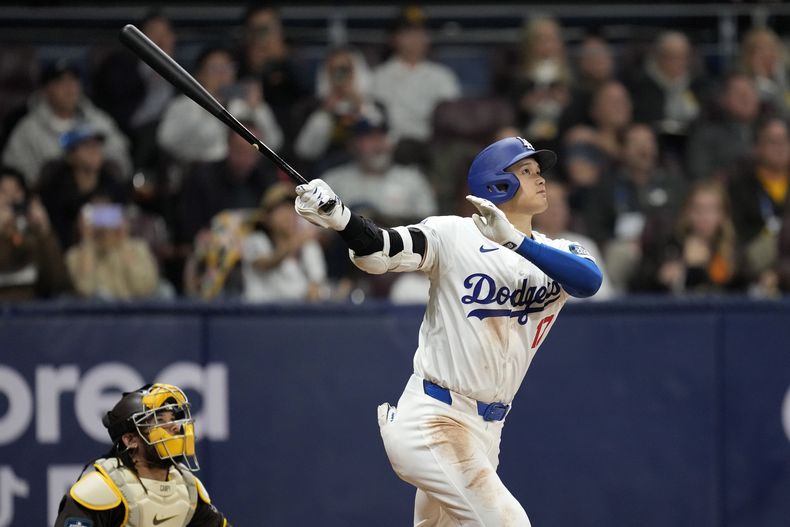 El bateador designado de los Dodgers de Los Ángeles Shohei Ohtani batea un elevado de sacrificio mientras lo observa el cátcher de los Padres de San Diego Luis Campusano en el encuentro del jueves 21 de marzo del 2024. (AP Foto/Lee Jin-man)