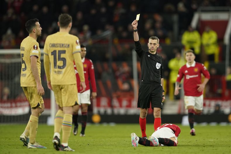El árbitro Clement Turpin le muestra la tarjeta amarilla a Sergio Busquets, del Barcelona, por una falta a Alejandro Garnacho, del Manchester United, durante el partido de vuelta de su serie de la Liga de Europa, el jueves 23 de febrero de 2023, en Manchester, Inglaterra. (AP Foto/Dave Thompson, Archivo)