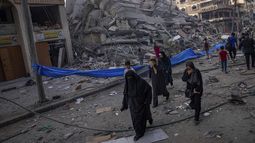 Palestinos caminan junto a un edificio en ruinas tras un ataque aéreo palestino en Ciudad de Gaza, el sábado 8 de octubre de 2023. El grupo Hamas, que gobierna la Franja de Gaza, realizó un ataque sin precedentes desde varios puntos contra Israel al amanecer del sábado, y lanzó miles de cohetes mientras docenas de combatientes se infiltraban en la fortificada frontera por aire, tierra y mar y tomaban al país por sorpresa en un importante feriado. (AP Foto/Fatima Shbair)