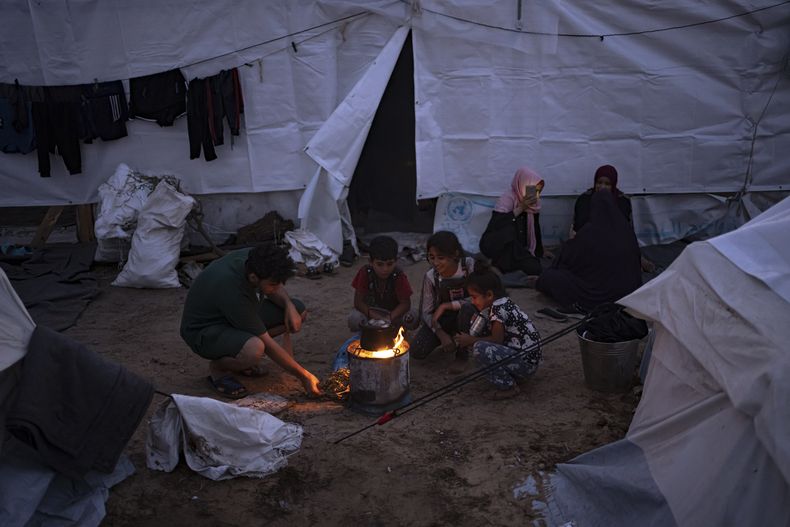 Palestinos desplazados por los bombardeos israelíes sobre la Franja de Gaza encienden una hoguera en un campamento de tiendas de campaña habilitadas por una agencia de la ONU, en Jan Yunis, el 31 de octubre de 2023. (AP Foto/Fatima Shbair)