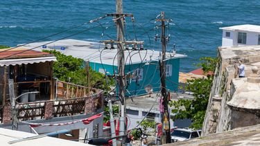 ARCHIVO - Líneas eléctricas y postes de servicios públicos frente al barrio de La Perla, en la costa del Viejo San Juan, Puerto Rico, el 15 de agosto de 2025. (Foto AP/Alejandro Granadillo, archivo)