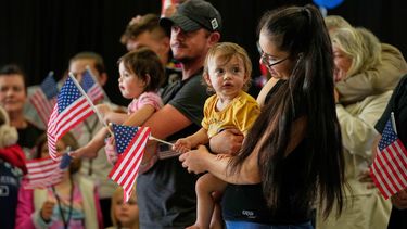 ARCHIVO – Refugiados afrikáners provenientes de Sudáfrica sostienen banderas estadounidenses a su llegada, el 12 de mayo de 2025, al Aeropuerto Internacional de Dulles, en la ciudad del mismo nombre, en Virginia. (AP Photo/Julia Demaree Nikhinson, File)