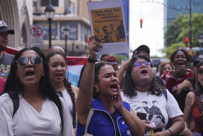 Varias personas protestan ante la sede de la fiscalía contra la desaparición de cuatro menores el pasado 8 de diciembre que huían de un convoy militar, en Guayaquil, el lunes 23 de diciembre de 2024. (AP Foto/César Muñoz)