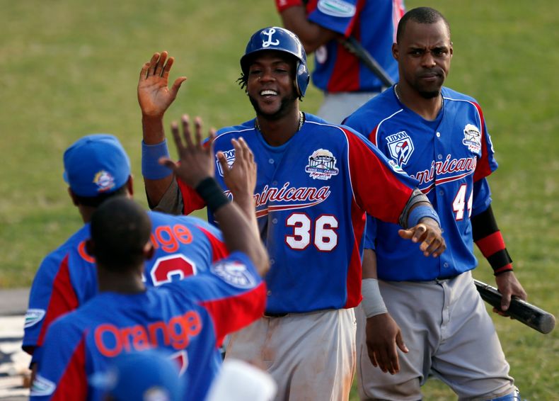 H&eacute;ctor G&oacute;mez (36), pelotero de cuadro de Rep&uacute;blica Dominicana, celebra con sus compa&ntilde;eros tras anotar una carrera contra Cuba en un juego de la Serie del Caribe, el lunes 3 de febrero de 2014, en Porlamar, Venezuela (AP Foto/Fe