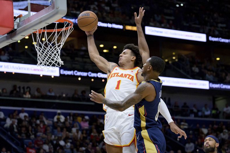 Jalen Johnson (1), de los Hawks de Atlanta, retaca el balón ante la presión defensiva de Jamal Cain (8), de los Pelicans de Nueva Orleans, durante la segunda mitad del juego de baloncesto de la NBA, el domingo 3 de noviembre de 2024, en Nueva Orleans. (AP Foto/Matthew Hinton)