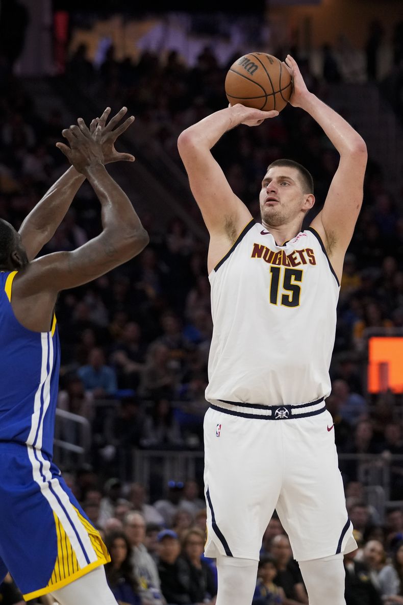 El pívot de los Nuggets de Denver Nikola Jokic lanza el balón sobre el pívot de los Warriors de Golden State Draymond Green en el encuentro de la NBA del domingo 25 de febrero del 2024. (AP Foto/Godofredo A. Vásquez)