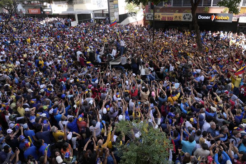 Partidarios de la líder opositora venezolana María Corina Machado rodean el camión desde el que saluda durante una protesta contra el presidente de Venezuela, Nicolás Maduro, en la víspera de su toma de posesión para un tercer mandato, en Caracas, Venezuela, el 9 de enero de 2025. (AP Foto/Ariana Cubillos)