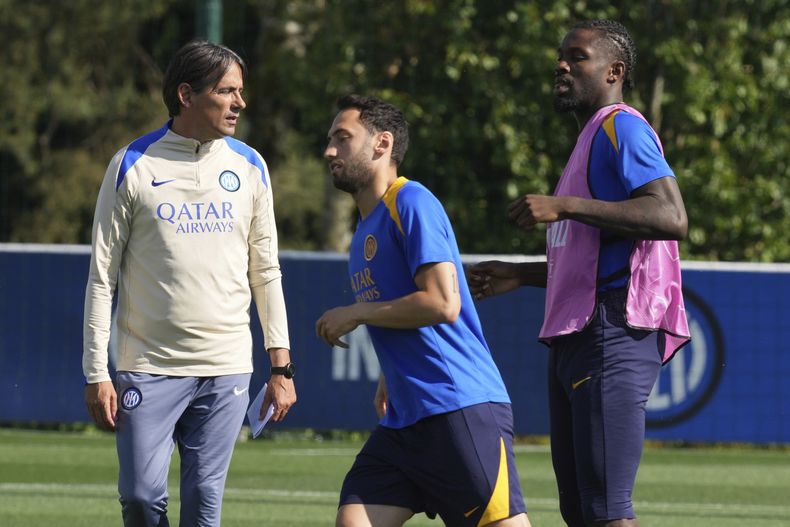 Simone Inzaghi, entrenador del Inter de Milán, observa el entrenamiento mientras Hakan Calhanoglu, centro, y su compañero Marcus Thuram realizan ejercicios en el Dia de Medios de la Liga de Campeones previo a la Final que se jugará el sábado contra el PSG, en la sede de entrenamiento del Inter, en Appiano Gentile, Italia, el lunes 26 de mayo de 2025. (AP Foto/Antonio Calanni)