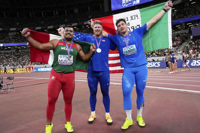 El medallista de plata mexicano Uziel Munoz, junto al medallista de oro estadounidense Ryan Couser y el medallista de bronce de Italia Leonardo Fabbri posan tras la final del lanzamiento de bala en el Mundial de Atletismo en Tokio el sábado 13 de septiembre del 2025. (AP Foto/Matthias Schrader)