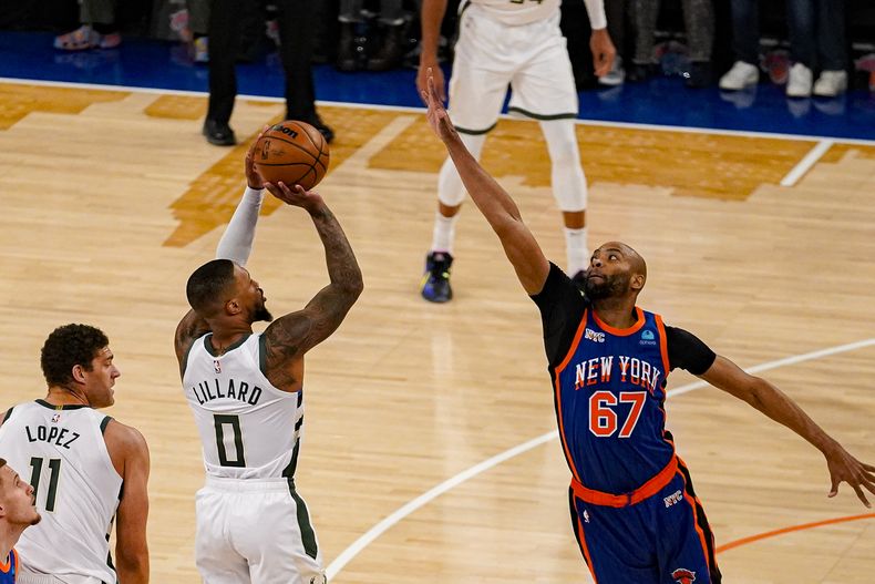 El base de los Bucks de Milwaukee Damian Lillard lanza el balón sobre el alero de los Knicks de Nueva York Taj Gibson en el encuentro de la NBA del sábado 23 de noviembre del 2023. (AP Foto/Peter K. Afriyie)