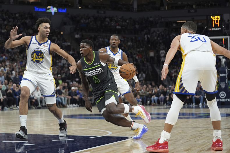 El base de los Timberwolves de Minnesota Anthony Edwards avanza hacia la canasta frente al alero de los Warriors de Golden State Trayce Jackson-Davis el domingo 24 de marzo del 2024. (AP Foto/Abbie Parr)