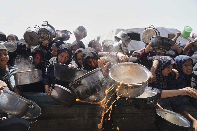 Palestinos tratan de conseguir comida donada en un comedor benéfico en Jan Yunis, Franja de Gaza, el lunes 5 de mayo de 2025. (AP Foto/Abdel Kareem Hana)