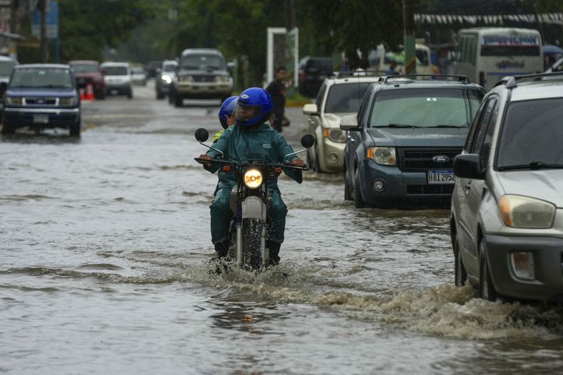 Un motociclista avanza en una calle inundada debido a lluvias generadas por la tormenta tropical Sara, el viernes 15 de noviembre de 2024, en La Lima, Honduras. (AP Foto/Moisés Castillo)