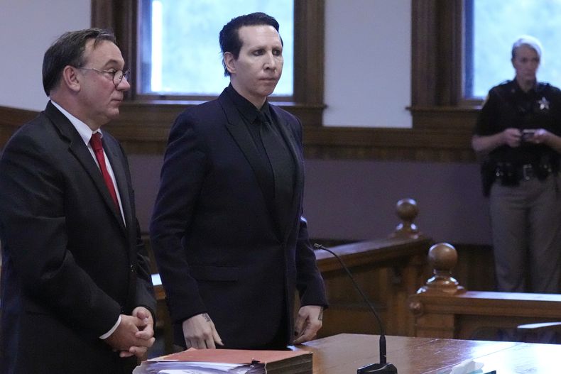 El músico Marilyn Manson, cuyo nombre verdadero es Brian Hugh Warner, centro, de pie con su abogado Kent Barker duranet una audiencia en la Corte Superior de Belknap el lunes 18 de septiembre de 2023, en Laconia, Nueva Hampshire. Marilyn Manson fue sentenciado a 20 horas de servicio comunitario y una multa el lunes por sonarse la nariz sobre una camarógrafa en un concierto de 2019 en Nueva Hampshire. (Foto AP /Charles Krupa)