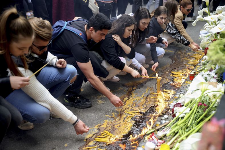 Estudiantes encienden velas cerca de la escuela Vladislav Ribnikar en Belgrado, Serbia, el jueves 4 de mayo de 2023. Muchos de ellos vestidos de negro y portando flores, los estudiantes rindieron un homenaje silencioso el jueves a sus compañeros asesinados un día antes cuando un niño de 13 años usó las pistolas de su padre para perpetrar un tiroteo en la escuela, incidente que conmocionó a todo el país y desató acciones para impulsar el control de armas de fuego. (AP Foto/Armin Durgut)