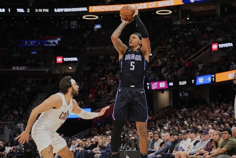 El alero del Magic de Orlando Paolo Banchero (5) dispara sobre el escolta de los Cavaliers de Cleveland, Max Strus, a la izquierda, en la segunda mitad el domingo 16 de marzo de 2025, en Cleveland. (AP Foto/Sue Ogrocki)