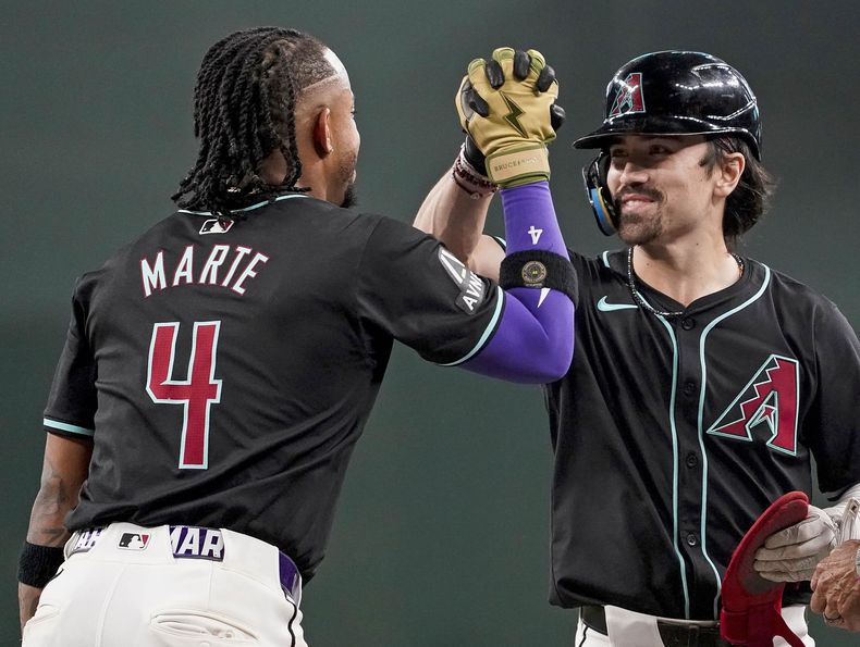 Durante un cambio de lanzador, Ketel Marte (4), de los Diamondbacks de Arizona, felicita a Corbin Carroll después de que éste bateara doblete en contra de los Atléticos de Oakland durante la séptima entrada del juego de béisbol, el domingo 30 de junio de 2024, en Phoenix. (AP Foto/Darryl Webb)