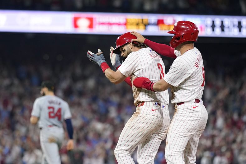 Bryce Harper (centro) y Whit Merrifield, de los Filis de Filadelfia, festejan el triunfo xobre los Nacionales de Washington, el sábado 18 de mayo de 2024 (AP Foto/Matt Slocum)