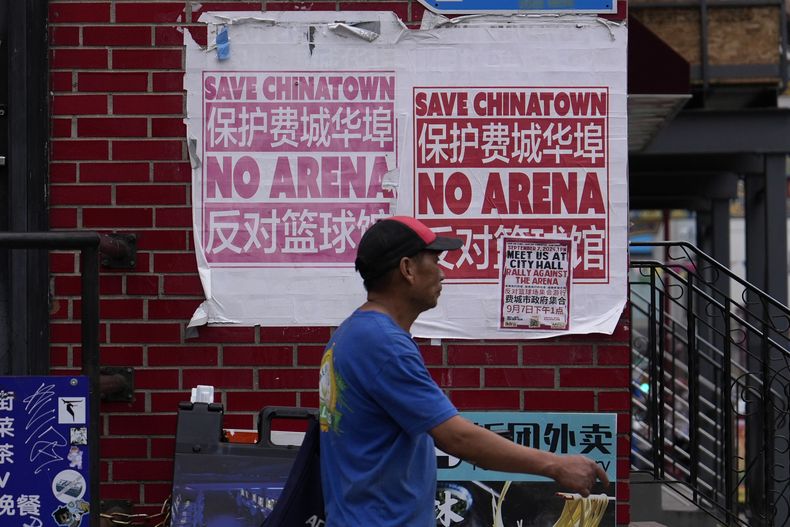 Un hombre camina en el Barrio Chino de Filadelfia, frente a un cartel que rechaza la propuesta de construir ahí una nueva arena para los 76ers, el miércoles 18 de septiembre de 2024 (AP Foto/Matt Slocum)
