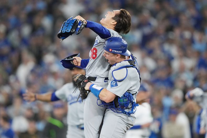 Yoshinobu Yamamoto (18), lanzador de los Dodgers de Los Ángeles, y Will Smith, receptor, celebran después de derrotar a los Azulejos de Toronto en el Juego 7 de la Serie Mundial de beisbol, el domingo 2 de noviembre de 2025, en Toronto. (Nathan Denette/The Canadian Press vía AP)