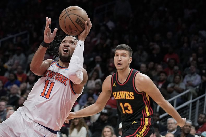 Jalen Brunson, base de los Knicks de Nueva York, intenta disparar frente a Saddiq Bey, alero de los Hawks de Atlanta, en el partido del miércoles 15 de noviembre de 2023 (AP Foto/Brynn Anderson)