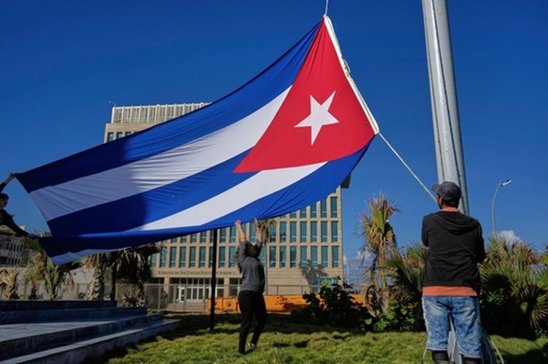 Trabajadores colocan la bandera cubana a media asta en la Tribuna Antiimperialista, cerca de la embajada de Estados Unidos en La Habana, el lunes 5 de enero de 2026, en memoria de los cubanos fallecidos dos días antes en Caracas durante la captura del presidente venezolano Nicolás Maduro por fuerzas estadounidenses. (Foto AP/Ramón Espinosa)