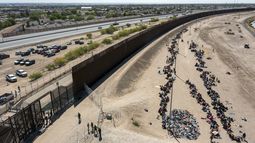 ARCHIVO - Migrantes forman filas frente a la valla en la frontera de Estados Unidos con México a la espera de ser transportados a una instalación de la Patrulla Fronteriza, el 10 de mayo de 2023, en El Paso, Texas. (AP Foto/Andrés Leighton, Archivo)