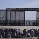Migrantes que cruzaron la frontera desde México hacia Estados Unidos esperan a un costado del muro fronterizo en donde agentes de la Patrulla Fronteriza de Estados Unidos montan guardia, el 30 de marzo de 2023, en una imagen tomada desde Cuidad Juárez, México. (AP Foto/Fernando Llano, Archivo)