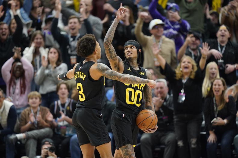 Jordan Clarkson (00), del Jazz de Utah, celebra con Keyonte George (3) durante la segunda mitad del juego de baloncesto de la NBA en contra de los Mavericks de Dallas, el lunes 1 de enero de 2024, en Salt Lake City. (AP Foto/Rick Bowmer)