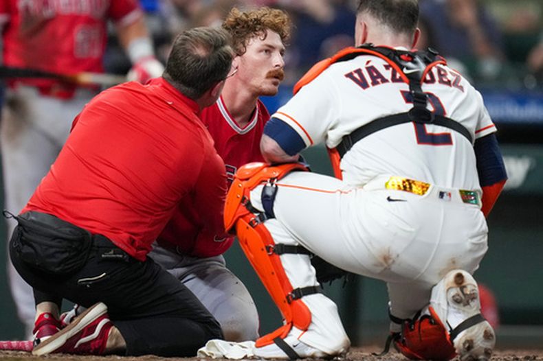 Wade Meckler, de los Angelinos de Los Ángeles, es revisado por un kinesiólogo, junto al boricua Christian Vázquez, receptor de los Astros de Houston, tras llevarse un pelotazo en el jueto del jueves 20 de agosto de 2026 (AP Foto/Eric Christian Smith)