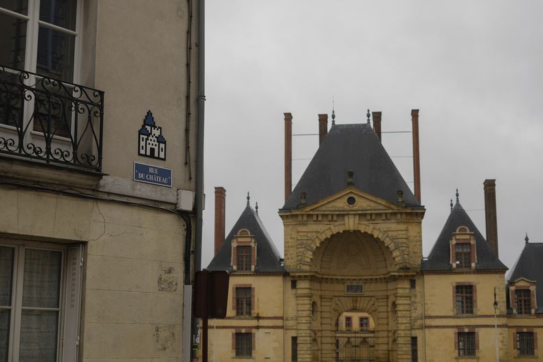 Un mosaico del artista francés Invader, arriba a la izquierda, en una calle de Fontainebleau, al sur de París, el jueves 29 de febrero de 2024. Invader, uno de los artistas franceses más internacionales, ha pegado mosaicos en las paredes de la capital francesa, el mundo e incluso los ha llevado a la Estación Espacial Internacional. (Foto AP/Thibault Camus)