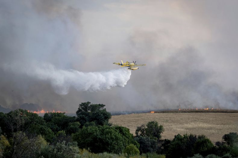 Una avioneta de bomberos arroja agua durante las labores para extinguir un incendio forestal cerca de Navalcarnero, en las afueras de Madrid, España, el jueves 17 de julio de 2025. (A. Pérez Meca/Europa Press vía AP)