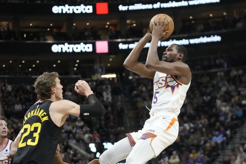 Kevin Durant, alero de los Suns de Phoenix, dispara mientras Lauri Markkanen (23), del Jazz de Utah, intenta defender durante la primera mitad del juego de baloncesto de la NBA, el domingo 19 de noviembre de 2023, en Salt Lake City. (AP Foto/Rick Bowmer)