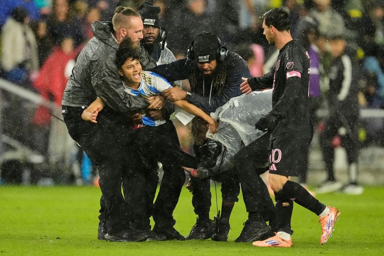 El argentino Lionel Messi estira la mano hacia un aficionado que fue detenido por invadir la cancha durante un partido de playoffs ante Nashville, el sábado 1 de noviembre de 2025 (AP Foto/George Walker IV)