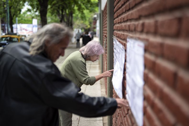 Las personas buscan sus nombres en las listas electorales antes de emitir su voto durante las elecciones generales en Buenos Aires, Argentina, el domingo 22 de octubre de 2023. (AP Foto/Rodrigo Abd)