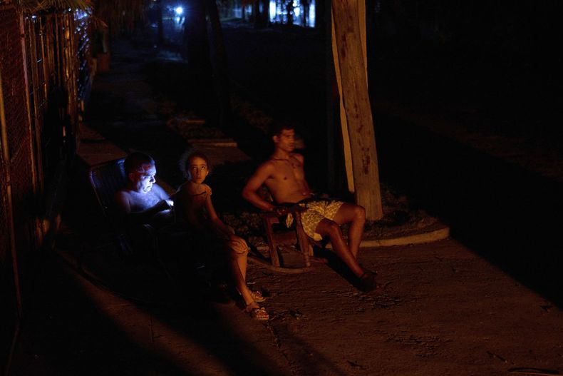 Tres personas sentadas al fresco en la noche fuera de sus casas durante un apagón en La Habana, Cuba, el miércoles 28 de mayo de 2025. (AP Foto/Ramón Espinosa)