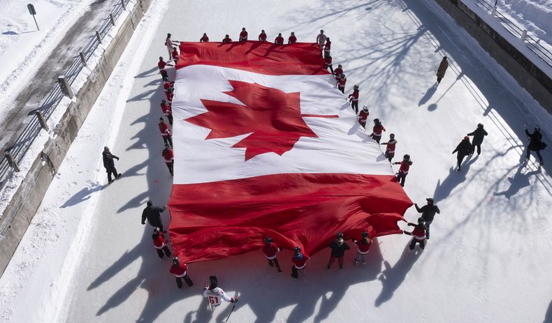 Jóvenes patinadores extienden una bandera canadiense en el Canal Rideau como parte de la conmemoración del 60mo aniversario de la bandera nacional, el viernes 14 de febrero de 2025 en Ottawa. (Adrian Wyld/The Canadian Press vía AP)