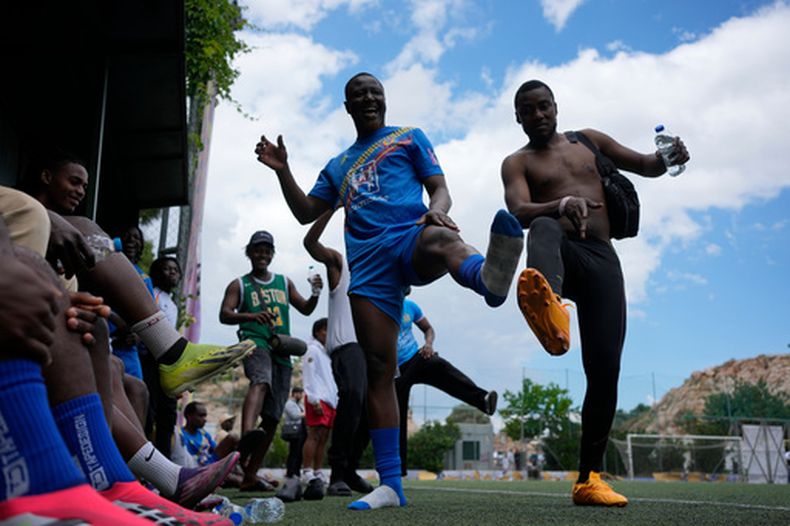 Migrantes procedentes del Congo bailan durante el partido semifinal ante Mali de la Copa Mundial Kypseli, el domingo 24 de mayo de 2026, en Atenas. (AP Foto/Thanassis Stavrakis)