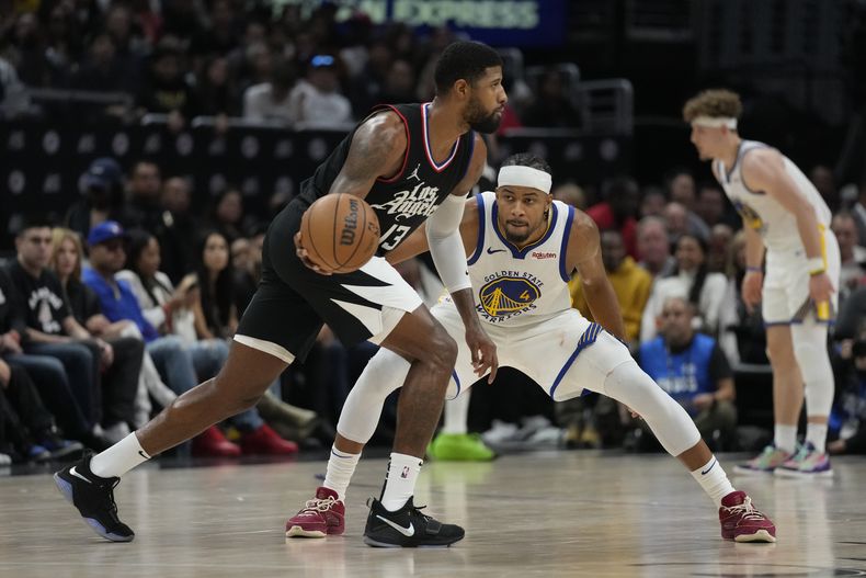 Paul George (13) de los Clippers de Los Ángeles controla el balón ante Moses Moody de los Warriors de Golden State, el sábado 2 de diciembre de 2023. (AP Foto/Ashley Landis)