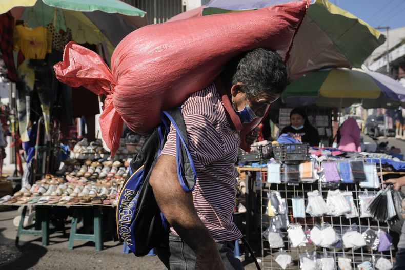 ARCHIVO - Un hombre carga un saco de maíz en el mercado de Comayaguela, en las afueras de Tegucigalpa, días después de las elecciones generales en Honduras, el 30 de noviembre de 2021. (Foto AP/Moises Castillo, Archivo)