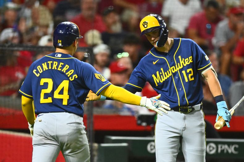 William Contreras, izquierda, de los Cerveceros de Milwaukee, celebra con Cooper Pratt, derecha, después de anotar con un doble productor de Andrew Vaughn (28) durante la séptima entrada del juego de béisbol de Grandes Ligas contra los Rojos de Cincinnati, el miércoles 24 de junio de 2026. (AP Foto/Ben Jackson)