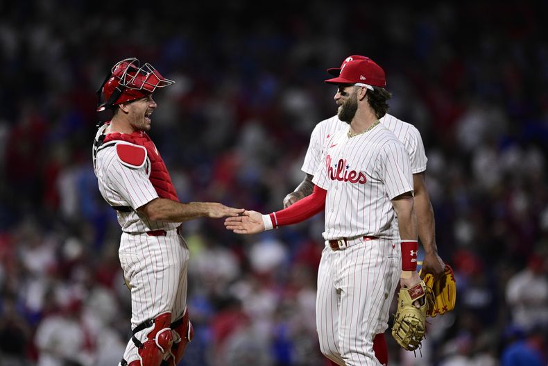 Bryce Harper, de los Filis de Filadelfia, a la derecha, y J.T. Realmuto, a la izquierda, celebran después de un partido de béisbol contra los Cardenales de San Luis, el sábado 1 de junio de 2024, en Filadelfia. (AP Foto/Derik Hamilton)