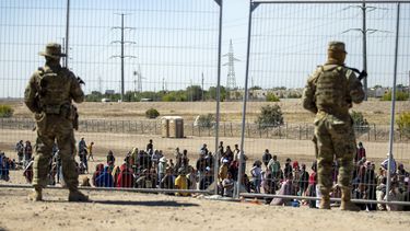 ARCHIVO - Migrantes esperan junto a una valla fronteriza bajo la vigilancia de la Guardia Nacional de Texas el 10 de mayo de 2023 para ingresar a El Paso, Texas. (AP Foto/Andrés Leighton)