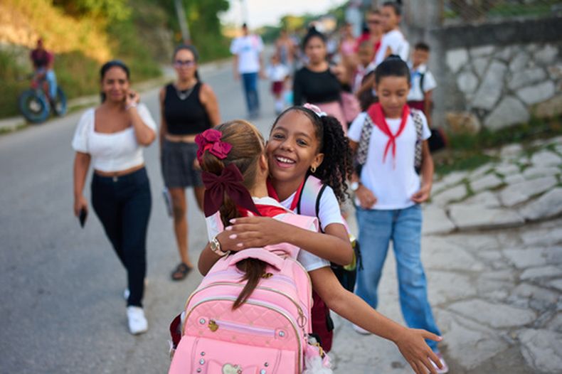 Unas niñas se abrazan al llegar a la escuela en su primer día de clases en Minas, en la provincia cubana de La Habana, el martes 1 de septiembre de 2026. (AP Foto/Ramón Espinosa)