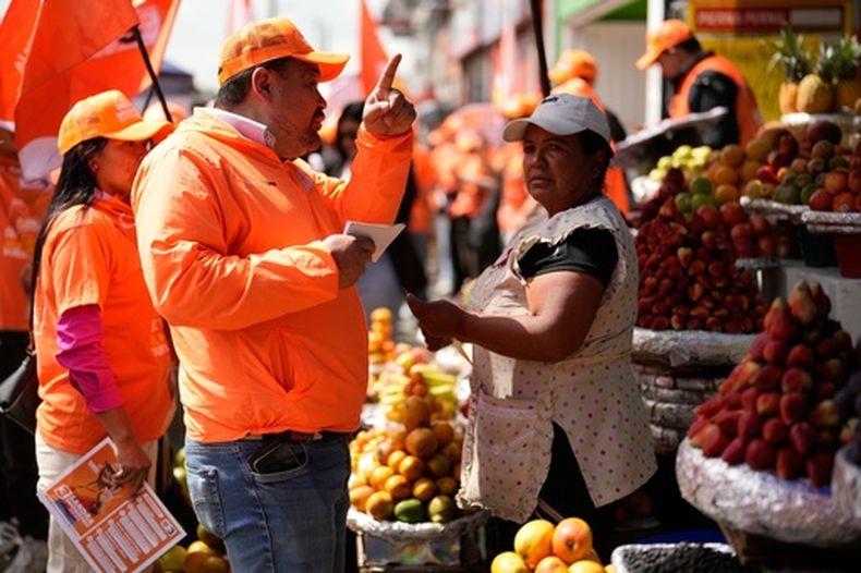 El congresista Carlos Carreño Marín, conocido como Sergio Marín, del partido Comunes, habla con una vendedora mientras hace campaña para la reelección antes de las elecciones legislativas en Bogotá, Colombia, el jueves 26 de febrero de 2026. (AP Foto/Fernando Vergara)