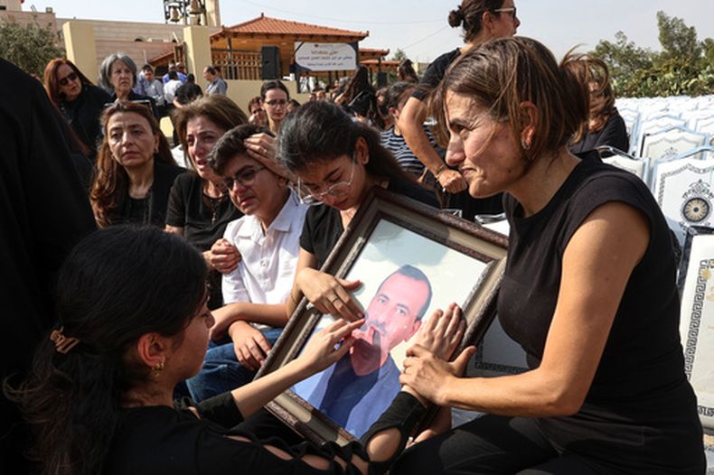 Parientes en duelo tocan un retrato enmarcado de una víctima del ataque a una iglesia ortodoxa griega, durante un funeral en Karak, Jordania, el domingo 25 de octubre de 2026. (AP Foto/Raad Adayleh)